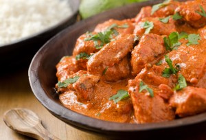 A delicious bowl of creamy butter chicken with basmati rice and cilantro.